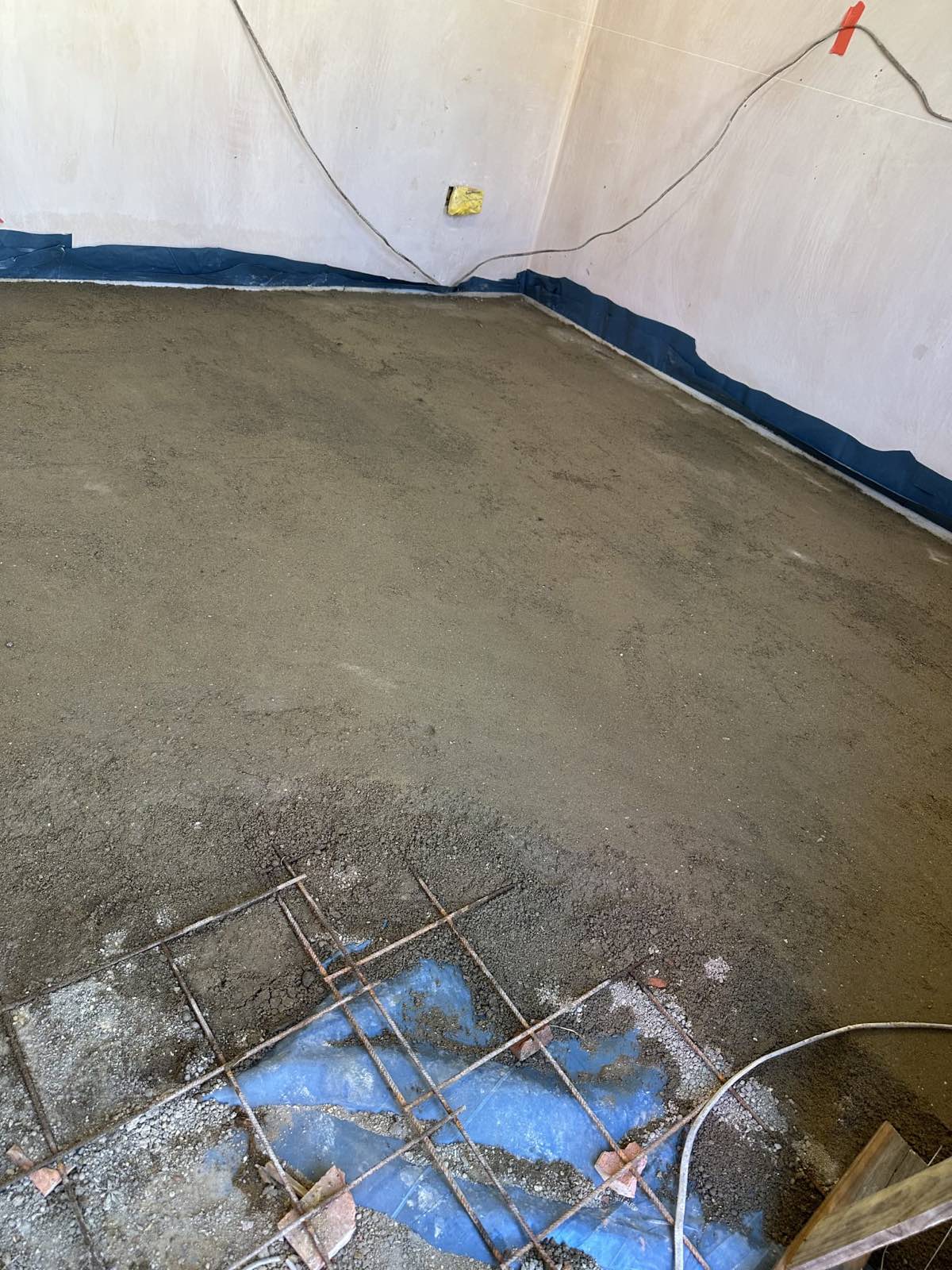 Sand and cement screed being laid over reinforcement mesh in a garage conversion