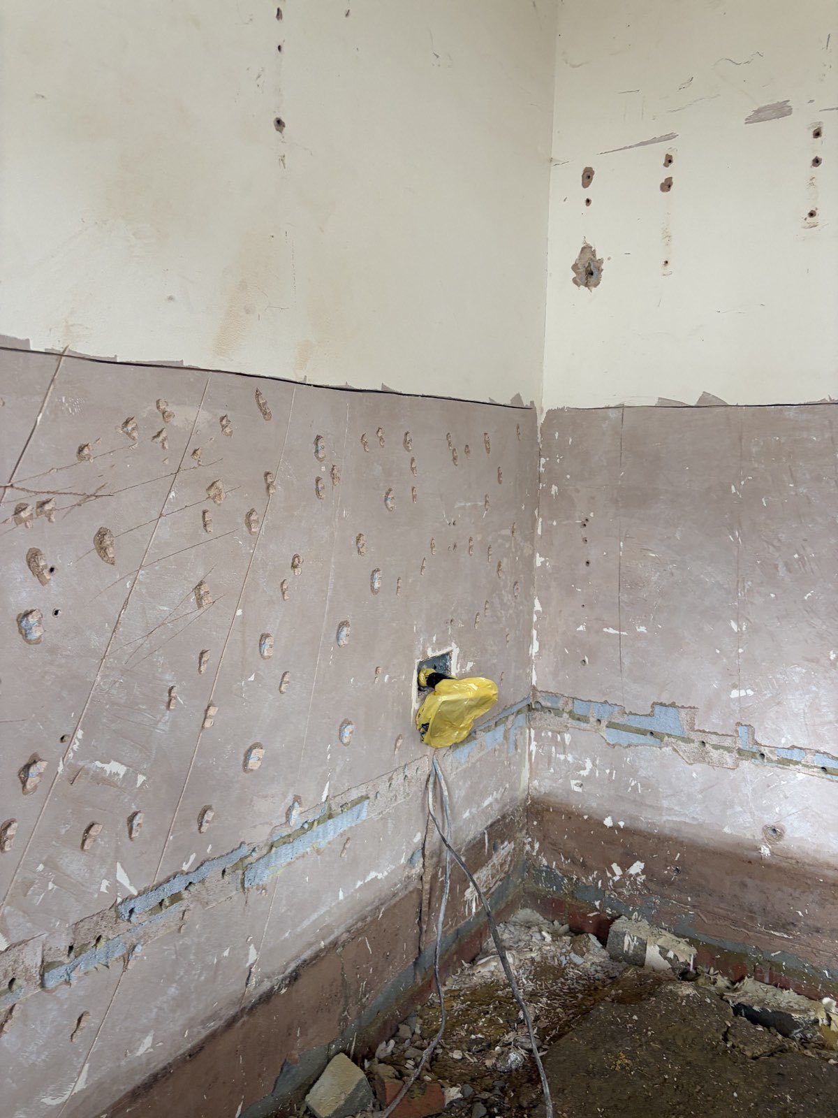 Chemical damp proof course injection holes drilled in a garage wall, Hendon NW4